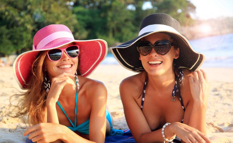 海滩上戴着太阳帽和太阳镜的比基尼美女
