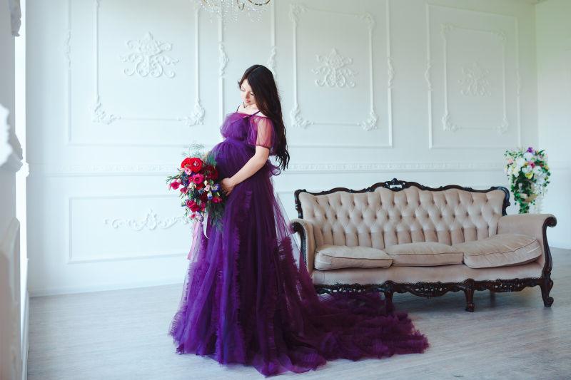奢华背景下穿紫色服装的美丽孕妇
