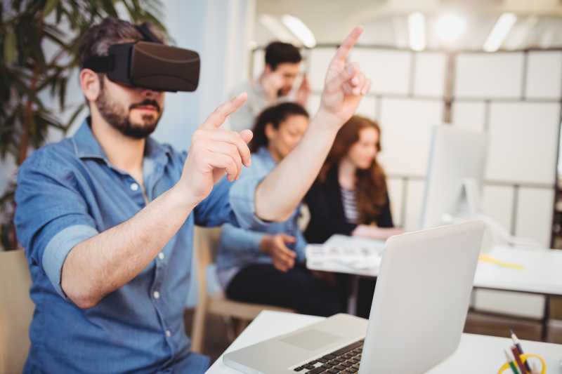 办公室里年轻的男人在使用VR眼镜
