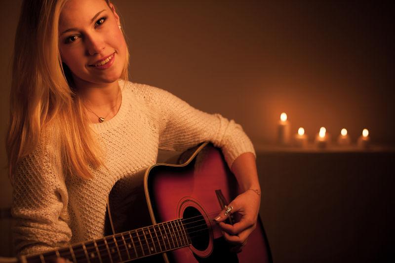 正在烛光下弹吉他的金发美女