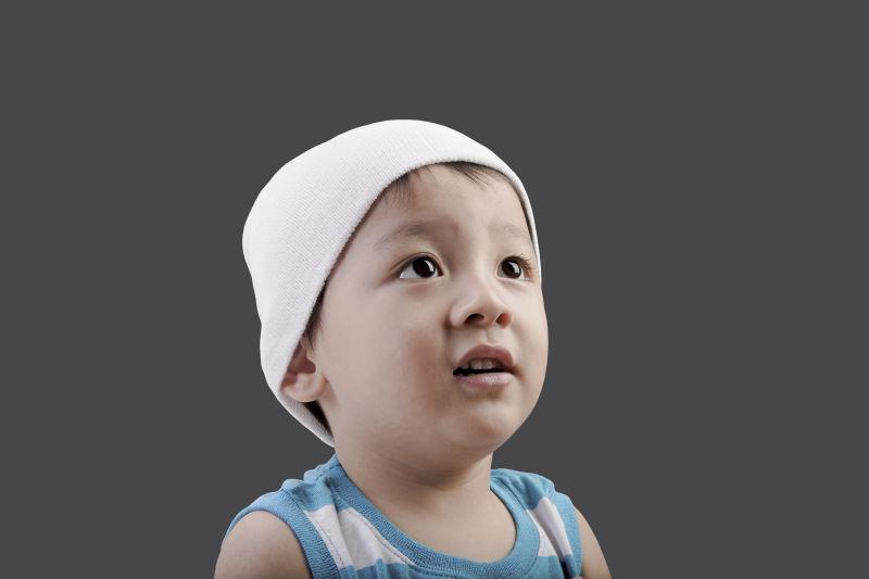 灰色背景下戴着白色帽子的儿童