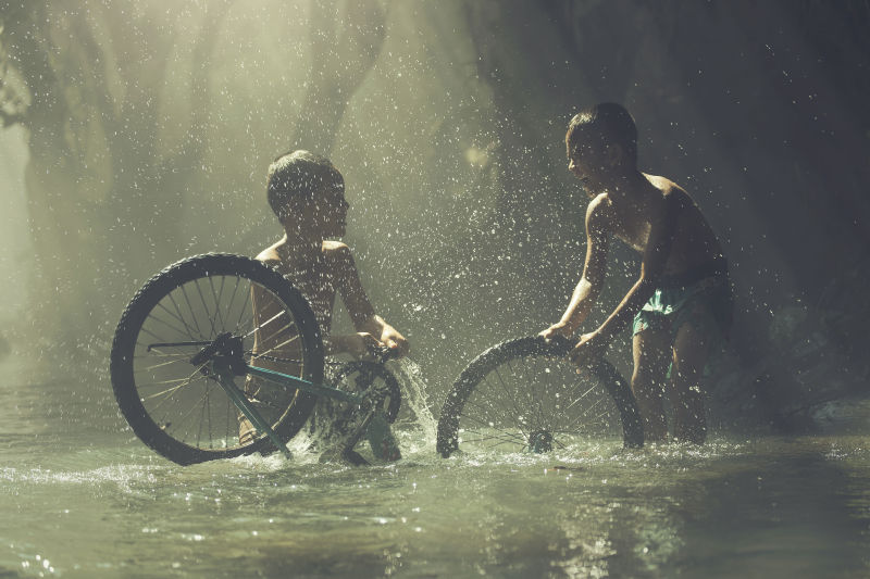 孩子们小溪里玩着自行车