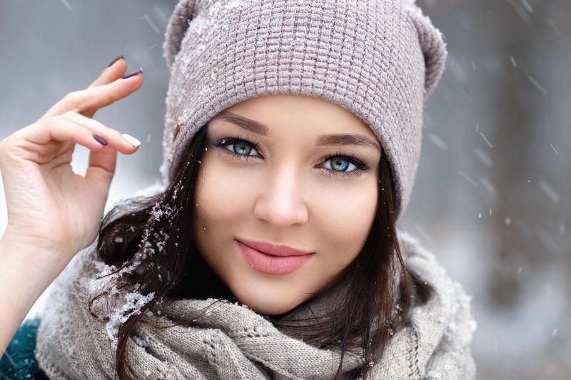 戴帽子的蓝色眼睛的美女在雪地里