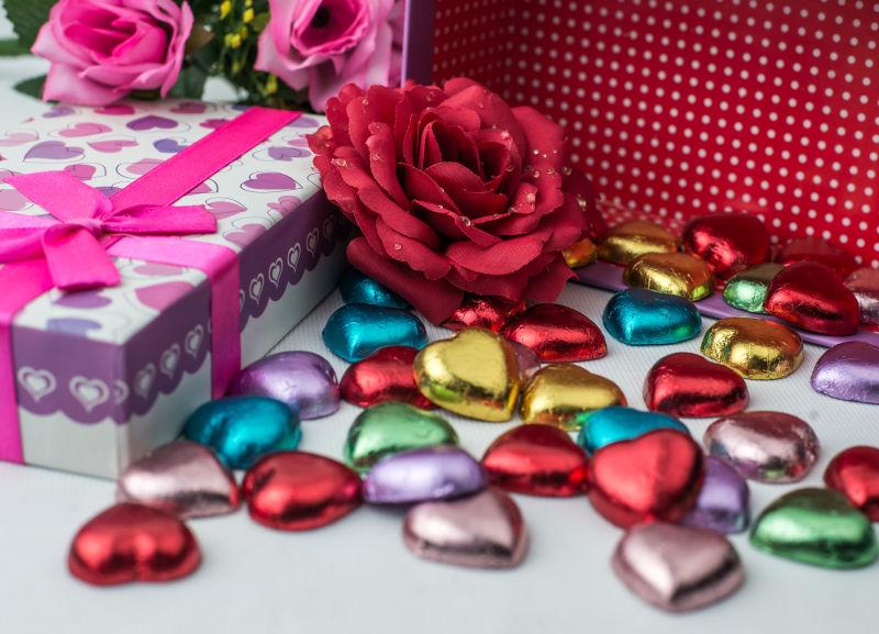 美丽的鲜花和彩色纸包裹的心形巧克力