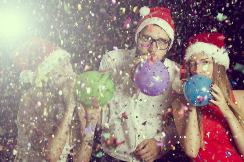 圣诞节装扮的一家人在彩带背景下吹气球