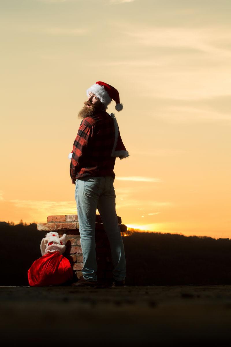 年轻帅哥装扮坏的圣诞老人往砖烟囱里小便
