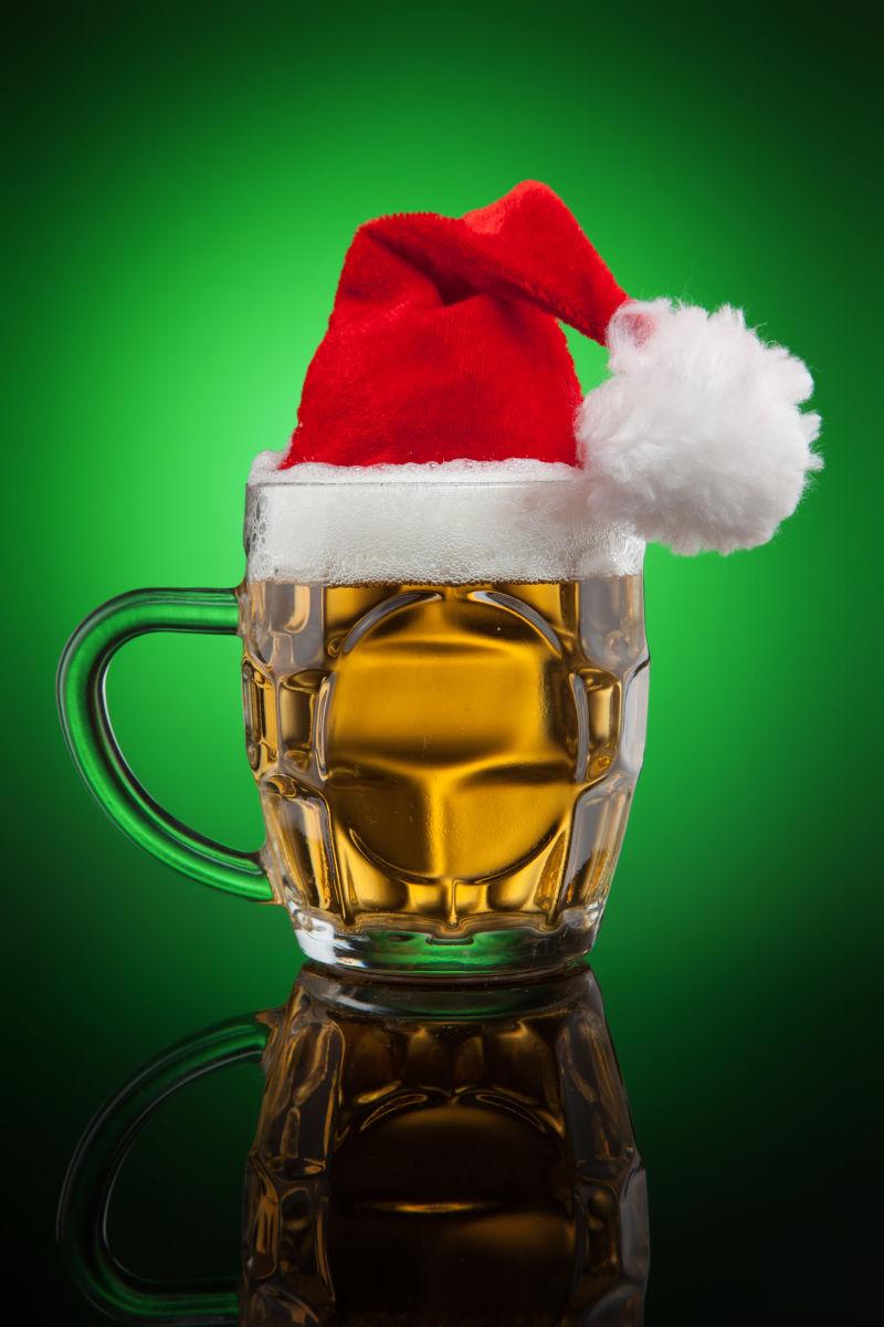 绿色背景前的圣诞帽和啤酒杯
