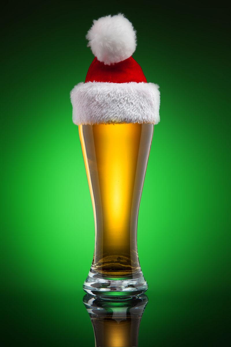 绿色背景前的圣诞帽子和啤酒杯