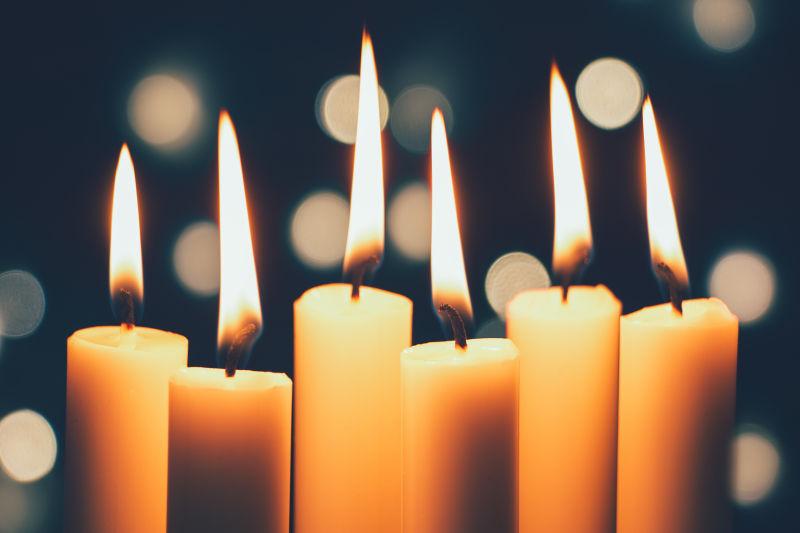 在圣诞节的背景下的燃烧的蜡烛与灯光
