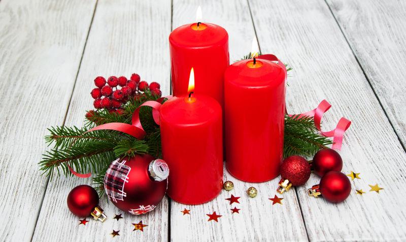 木桌上的燃烧的红烛松树圣诞装饰