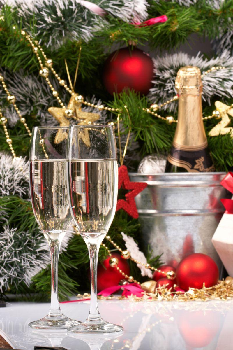 挂满装饰品的圣诞树下有一对香槟酒杯