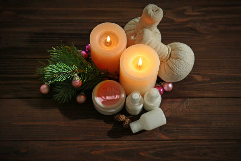 有圣诞节装饰品的木桌上的蜡烛和护肤品