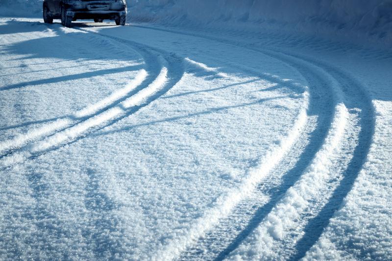 阳光下冬季雪地上的汽车轮胎印记