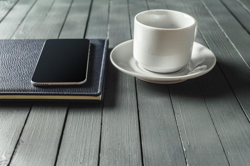 白色咖啡杯和笔记本手机