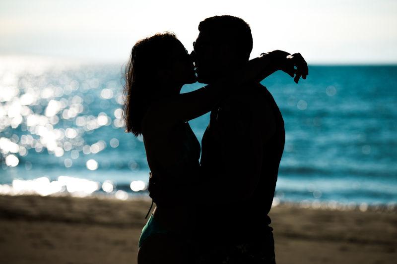 日落时海滩上情侣的剪影