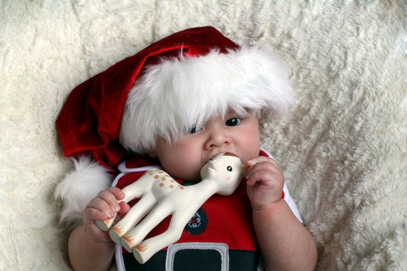 戴圣诞帽的可爱宝宝拿着一只鹿宝宝玩具