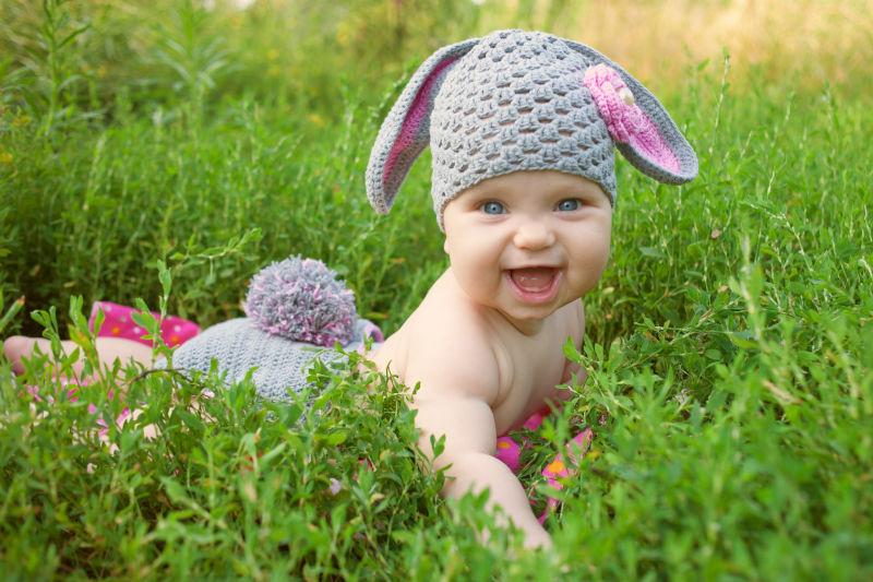 草地上的可爱婴儿穿着像兔子一样的衣服