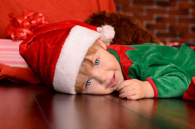 穿着圣诞节日服装的小男孩趴在地上