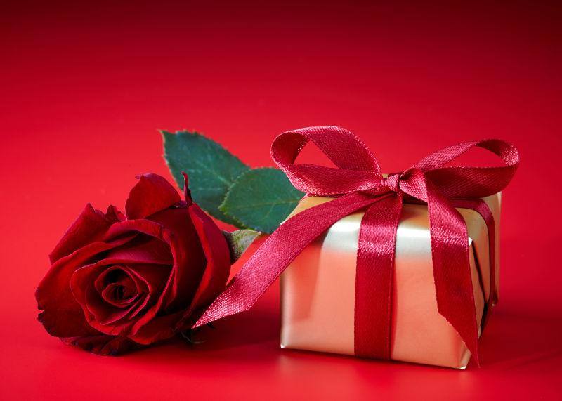 红色背景下的金色的礼品盒和红色的玫瑰