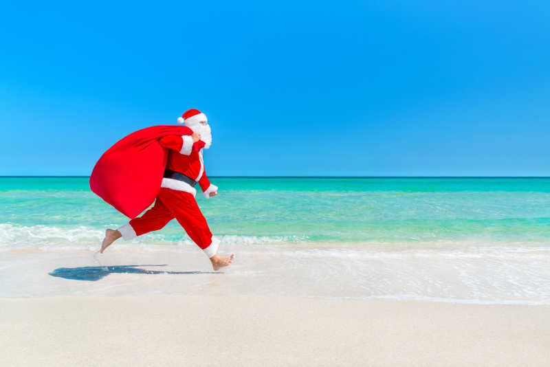 圣诞老人带着满满一包礼物的海滩漫步