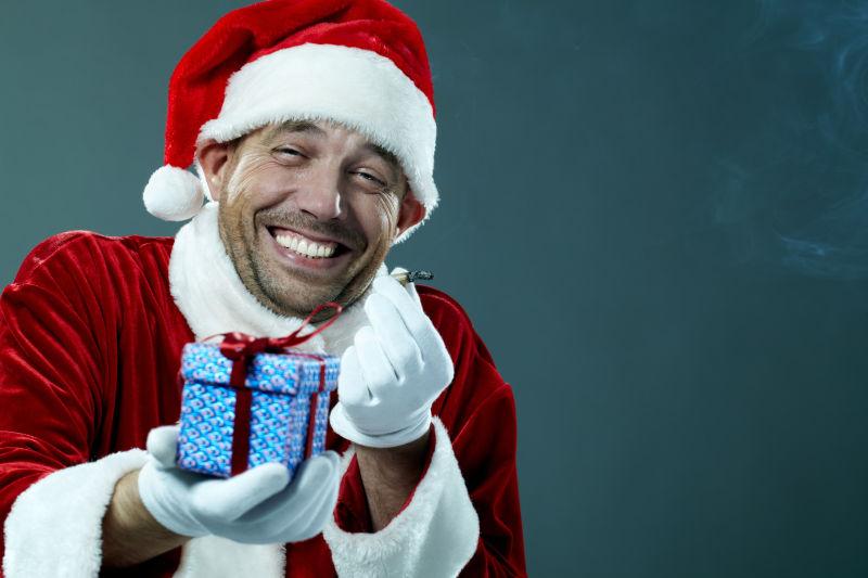 身穿圣诞老人服装的男人微笑着拿礼物