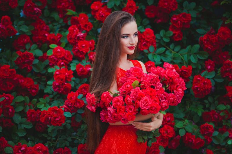 玫瑰背景前的美女拿着花朵