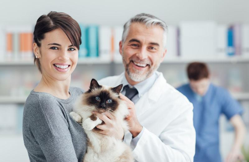 一位面带微笑的妇女和她的猫在兽医诊所