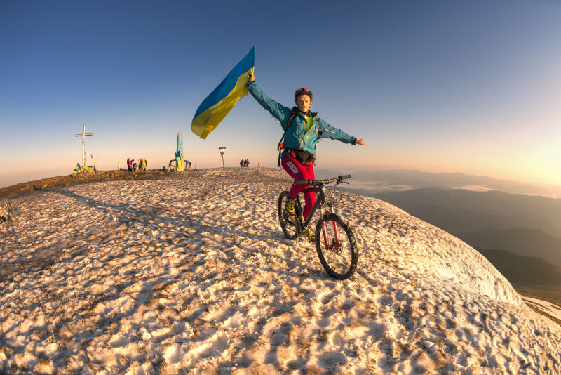 极限自行车运动运动员在山顶挥舞旗帜