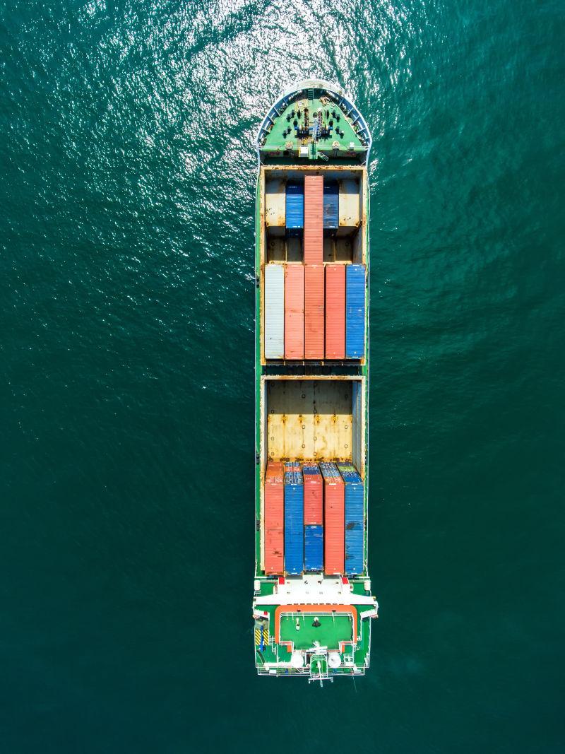 橄榄绿色海面上载着彩色集装箱的船只