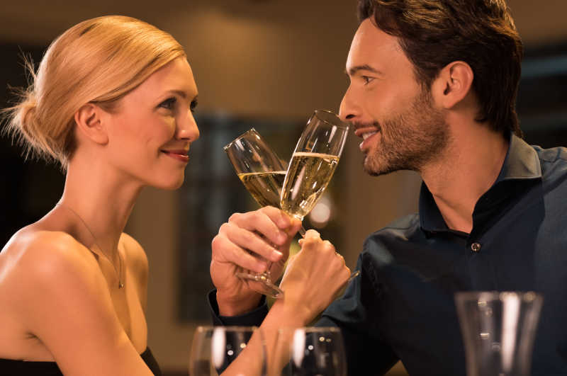 年轻的快乐夫妇在豪华餐厅浪漫的约会时喝杯香槟