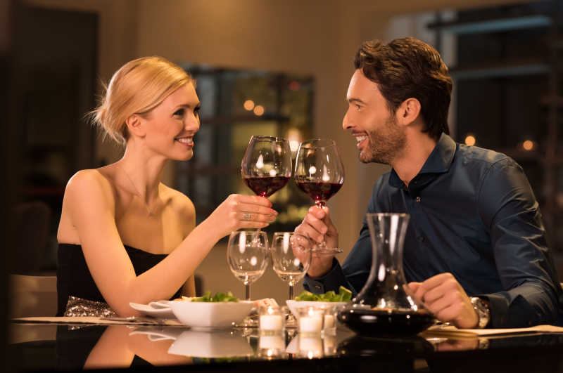 浪漫的年轻夫妇在饭店里举杯祝酒