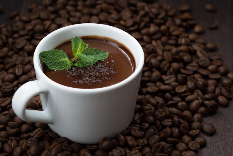 咖啡豆背景下用薄荷装饰的一杯热巧克力