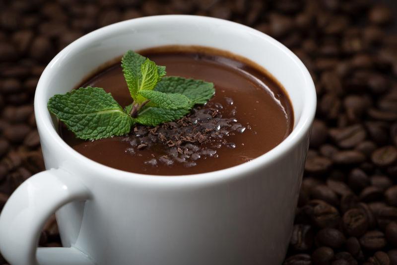 咖啡豆背景下薄荷装饰的一杯热巧克力