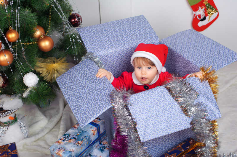 圣诞树边的礼物盒里有小女孩