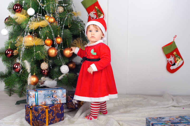 可爱的圣诞小女孩在圣诞树边