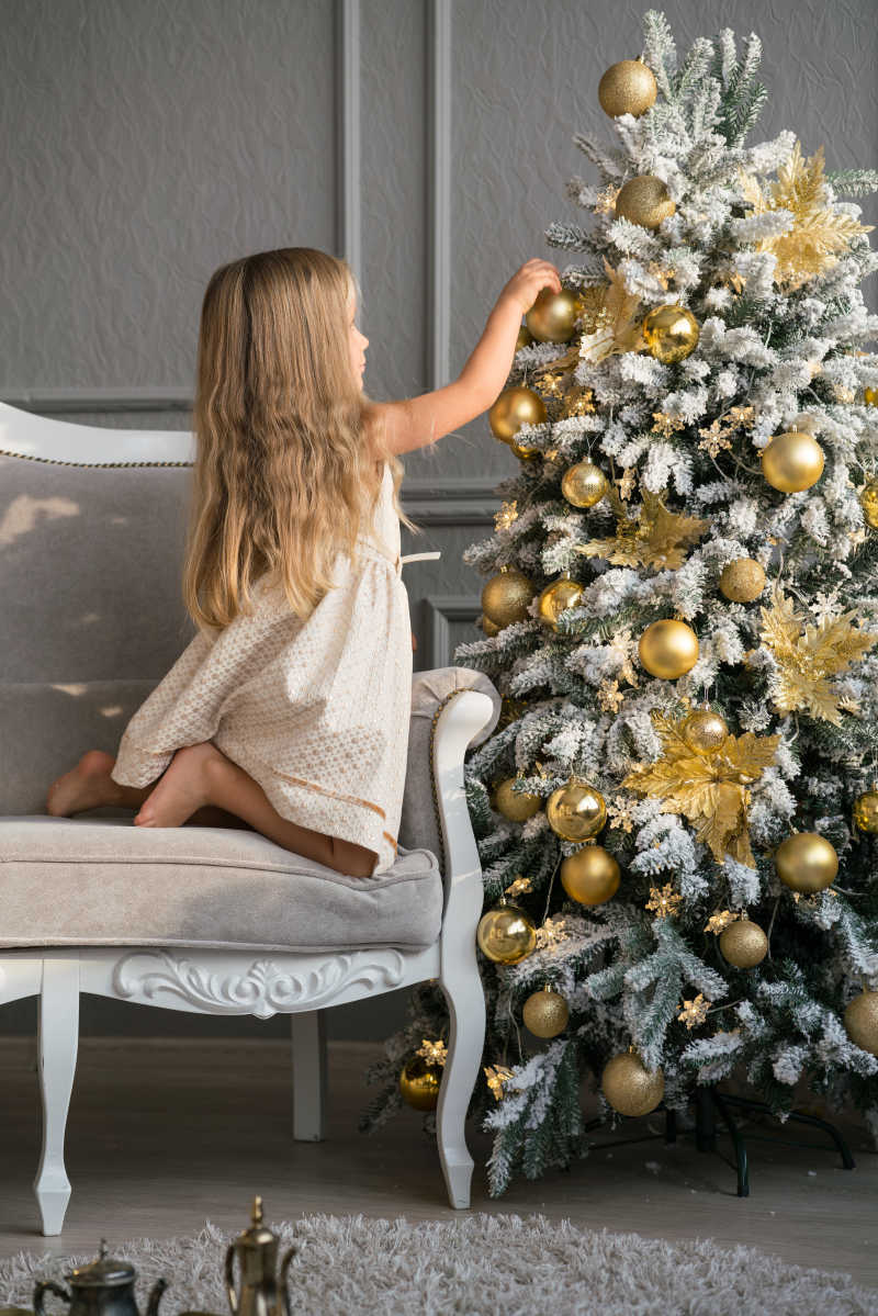 可爱的小女孩在圣诞树附近的室内