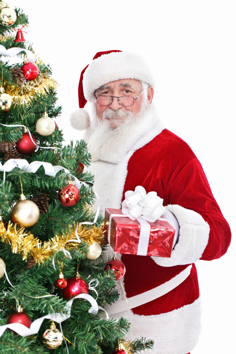 圣诞老人拿着礼物站在圣诞树旁边