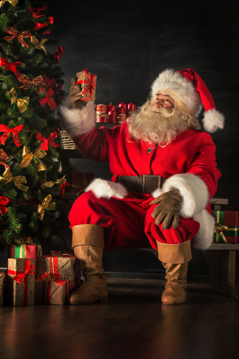 圣诞老人在圣诞树旁边摆放礼品
