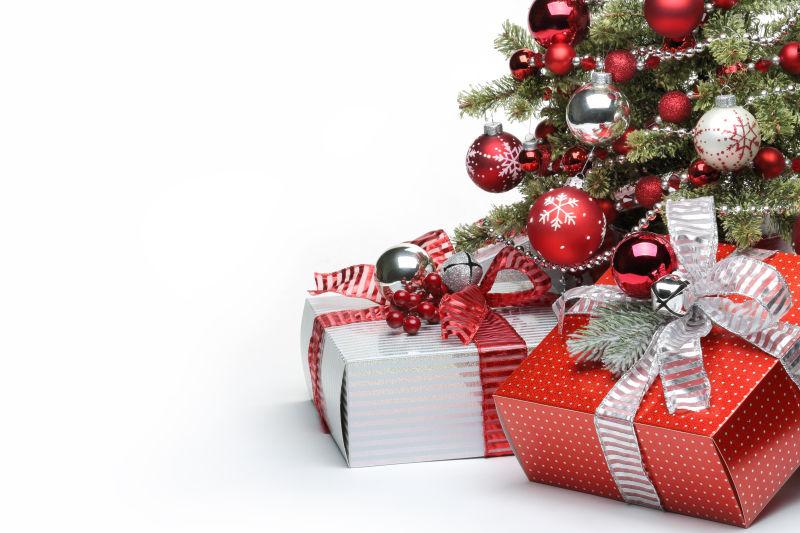 白色背景下带着红色小球装饰的圣诞树和礼物盒