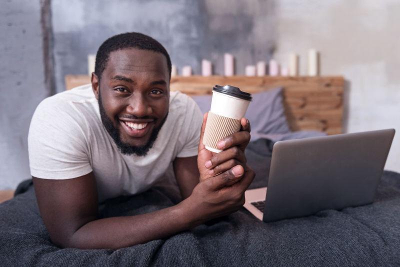 快乐的黑人在卧室里捧着一杯咖啡